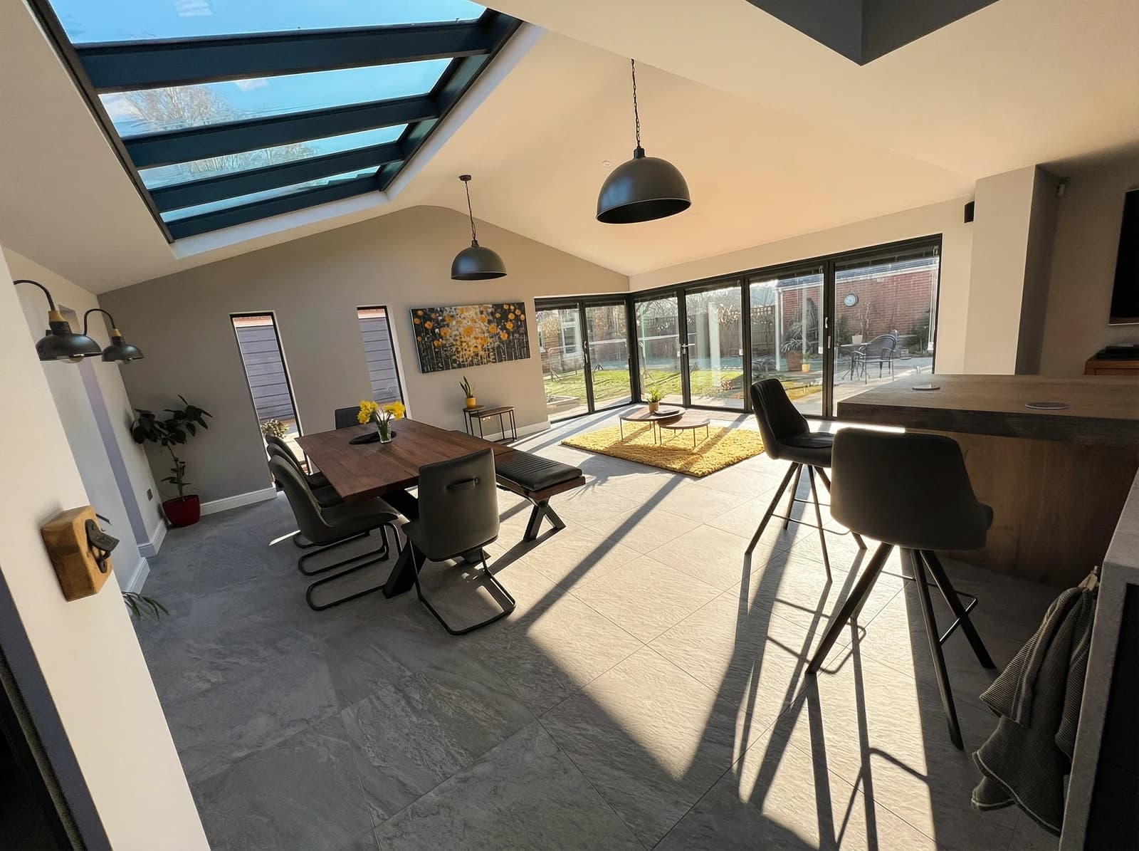 The finished open-plan dining area of Ian's kitchen extension, bifold doors open to the garden