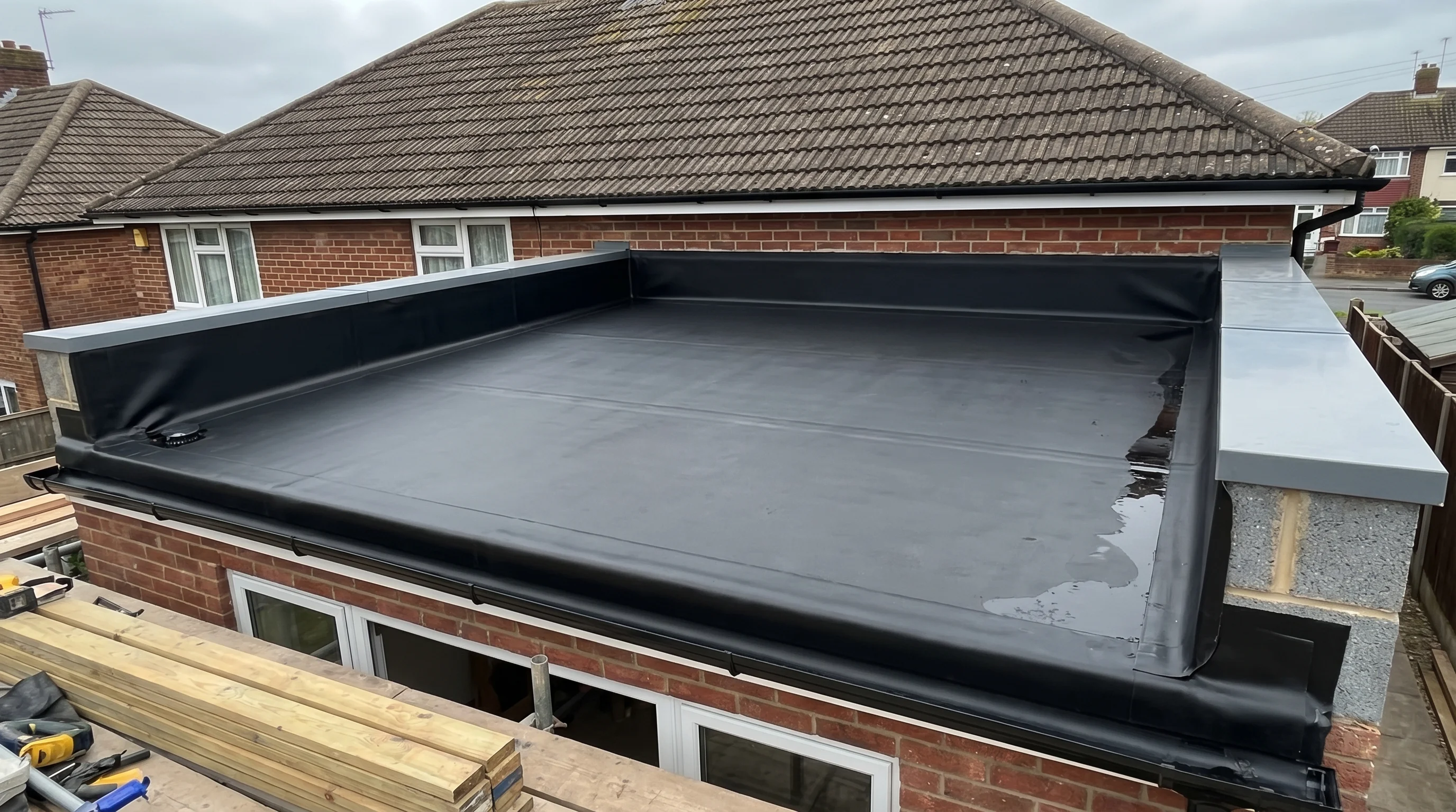EPDM rubber membrane installed on a flat roof, showing the seamless black rubber sheet bonded across the deck and trimmed at the edges