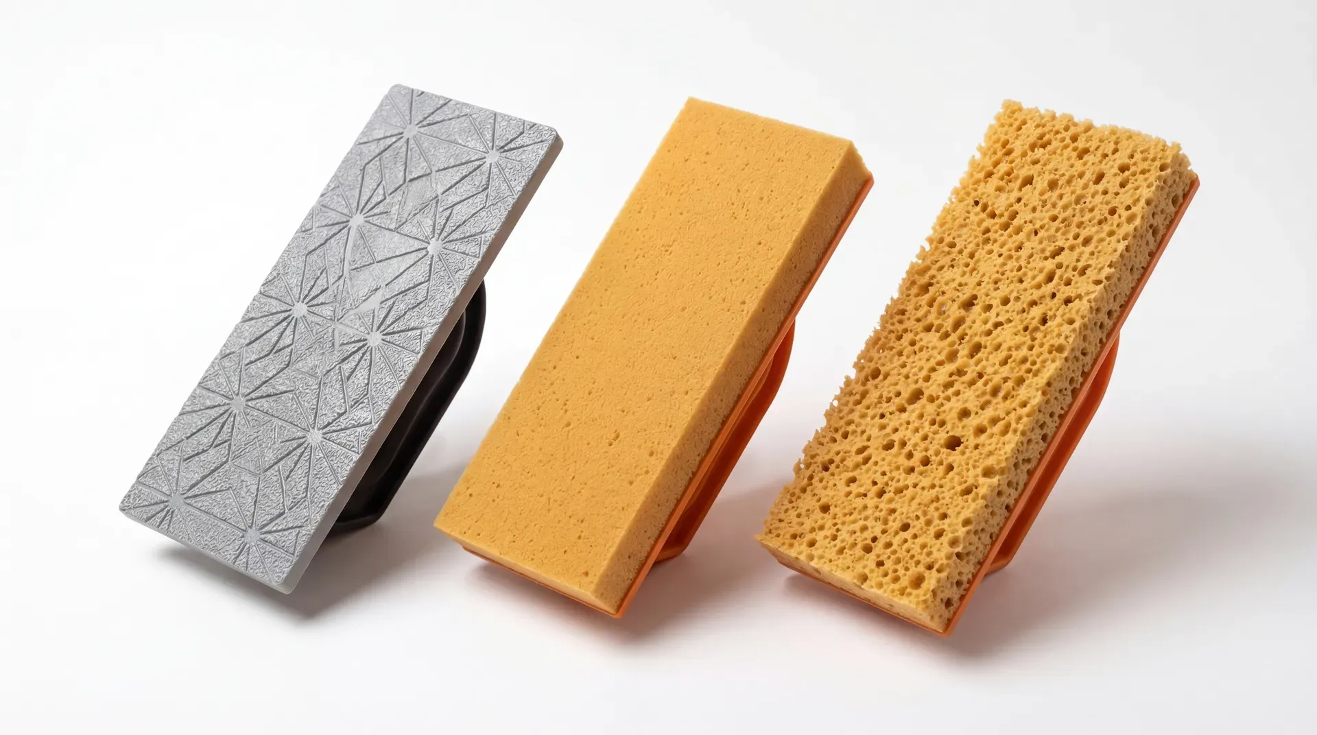 Three plastering floats arranged in a row: a polyurethane poly float with a grey patterned non-absorbent face, a fine sponge float with smooth tight-cell rubber sponge, and a coarse sponge float with large open-cell pores. Each is approximately 280mm by 140mm.